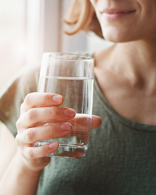 Zolben - Mujer sosteniendo un vaso lleno de agua para tomar un comprimido